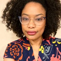 A black woman wearing glasses and a colourful shirt